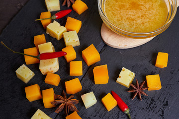 pieces of different cheese with honey on a stone plate