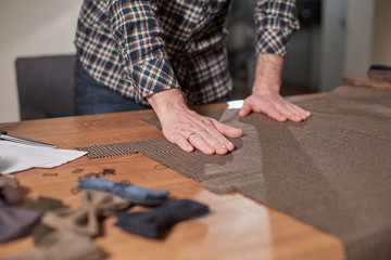 Close-up hands of Tailor, cutting wool fabric. Craftsman Makes rectangular blanks for Bow ties of woolen fabric. Work with sewing machine in a textile studio.