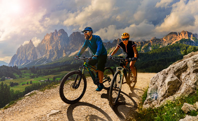 Cycling woman and man riding on bikes in Dolomites mountains andscape. Couple cycling MTB enduro...