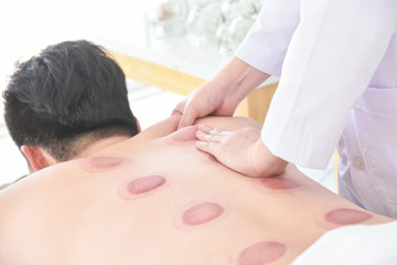 Therapist doing Tui na massage for her patient after cupping therapy finished ,Chinese alternative...
