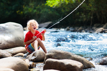Child hiking in mountains. Kids at river shore.