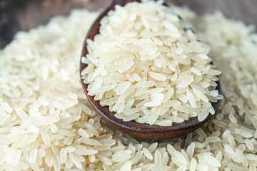 White rice with a wooden spoon on a pile of rice against the background of old boards. Jasmine rice for cooking.