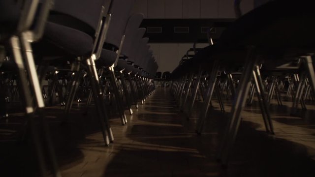 Walking through a row of empty seats in a conference hall