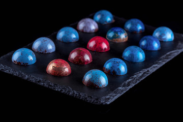  Handmade multicolored chocolate candies in glaze. Black background. Close-up.