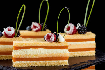 Beautiful cakes decorated with berries. Black background. Close-up.