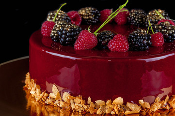  Celebratory cake decorated with burgundy glaze and fruit. Close-up.