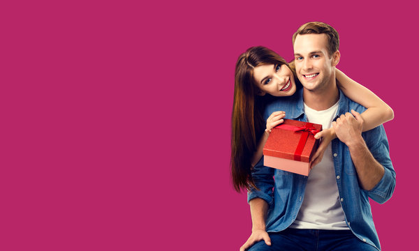Love, relationship, dating, flirting, lovers concept - happy smiling amorous couple opening gift box. Over red color background. Copy space for some text.