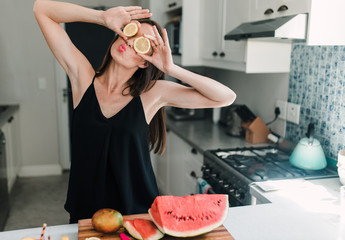 Beautiful woman holding lemon slices in front of her eyes and pouting