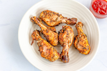 Baked Chicken Legs with Tomato Ketchup on a White Background, Top View Close Up Photo.
