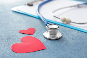Clipboard with stethoscope and hearts on color background. Cardiology concept