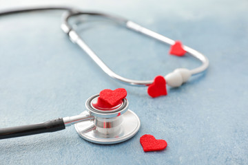 Stethoscope and hearts on color background. Cardiology concept