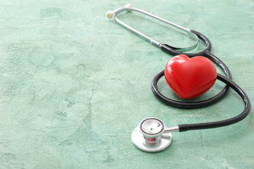 Stethoscope and heart on color background. Cardiology concept