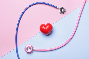 Stethoscopes and heart on color background. Cardiology concept