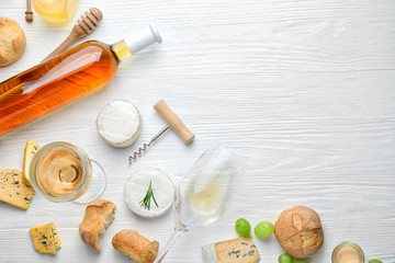 Delicious wine with snacks on white wooden background