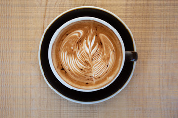 A flat lay black cup of coffee placed on a wooden table by the window in shop,