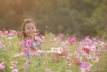 traveler or tourism. happy little asian girl child in cosmos flower fields  with big smile and laughing healthy happy funny smiling face young adorable lovely female kid.  happy lifestyle concept.