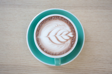 A flat lay green cup of coffee placed on a wooden table by the window in shop,