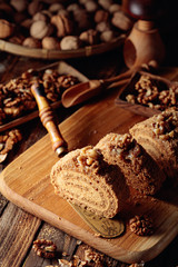 Walnut cake, nuts and wooden kitchen utensils on a wooden table.