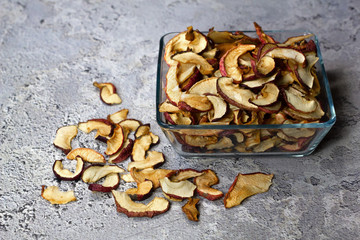 Dried Apple chips in a square glass plate on a gray concrete background. Organic natural food. side view