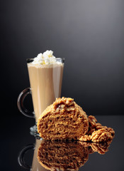Walnut cake and coffee latte with cream on a reflective background.