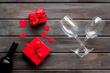 Valentines Day concept with wine, glasses, red present box on dark wooden background top-down