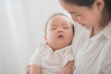 happy loving family. mother playing with her baby in the bedroom. asian mother hugging and holding her baby. family, motherhood, parenting, family and child care concept. White background.