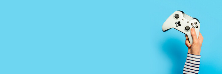Female hand hold a gamepad on a blue background. Concept of the game, e-sports, leisure, gaming...