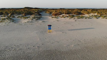 Aerial, orbit, drone shot, around a lifeguard post, at a beach, on a sunny evening, in Langeoog, Germany