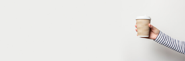 female hand holds a paper cup on a white background. Banner