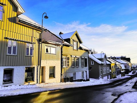 Road surrounded by houses covered in the snow under the sunlight and a blue sky in Larvik in Norway