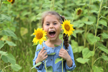 photo of a six year old girl laughing with her mouth wide open against a sunflower field
