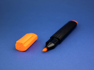 orange marker on a blue background with an open lid