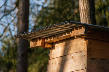 Wooden forest hide in the forest with metal roof