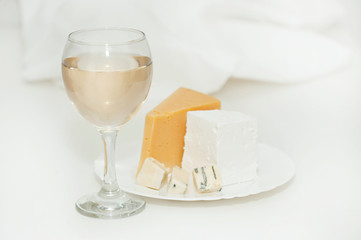 Glass of white wine and cheese on a plate