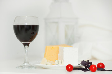Glass of red wine and cheese on a plate