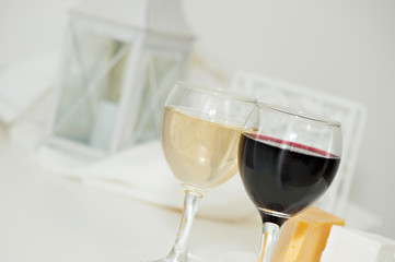 Glasses with red and white wine and cheese on a plate