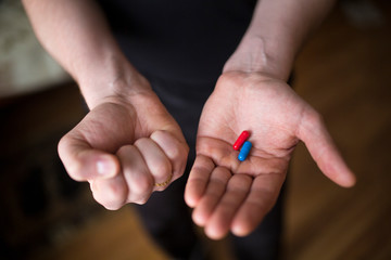 two pills in hands, red and blue