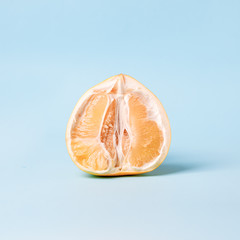 Half of fresh pomelo citrus on color blue background. Erotic concept, vagina idea, woman intimate...