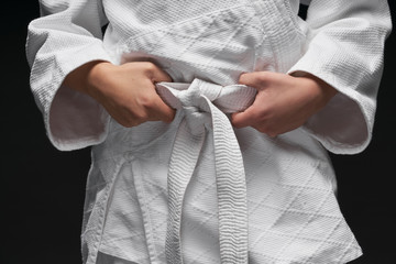 hands closeup - teenager dressed in martial arts clothing posing on a dark gray background, a...