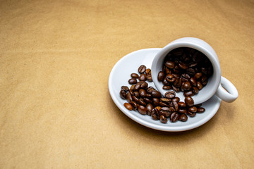 fallen full white cup of coffee beans on a beige background