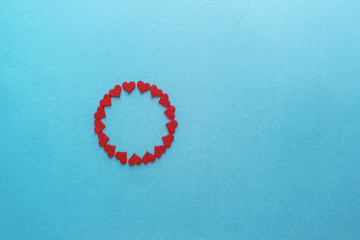 Valentine's Day. Red small hearts in the form of a circle on a blue surface. Top view.