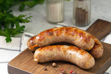Grilled sausages on a wooden Board on a light gray kitchen table