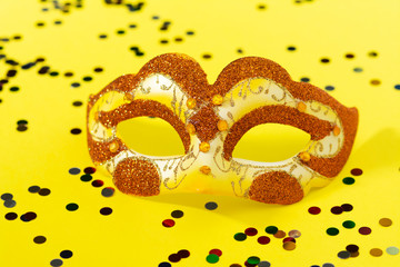 Yellow or gold carnival mask on a yellow background. Mask for the Venice festival. The Background Of Mardi Gras. Space for text