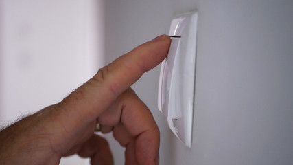 Businessman Hand Pushing On the Light Switch from Office Room Wall