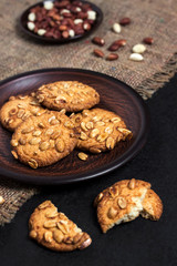 Homemade peanut cookies on a brown plate with raw peanuts in background