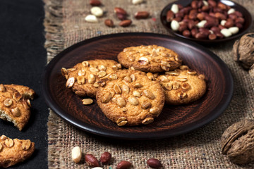 Homemade peanut cookies on a brown plate with raw peanuts in background