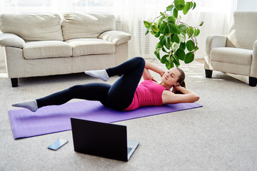 Beautiful young woman training online at home on laptop computer, copy space. Full length portrait....