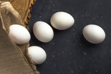 Easter flat lay rustic composition of fresh white eggs in egg cell  on dark background. Zero waste, eco friendly and natural material. Farming and healthy eating concept. Close up