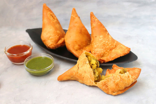 Vegetarian Aloo samosa or samosas. Indian special traditional street food. Famous Indian Punjabi samosa filled with spicy boiled potato mixture. served with green and red chutneys. Copy space.