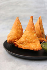 Vegetarian Aloo samosa or samosas. Indian special traditional street food. Famous Indian Punjabi samosa filled with spicy boiled potato mixture. served with green and red chutneys. Copy space.